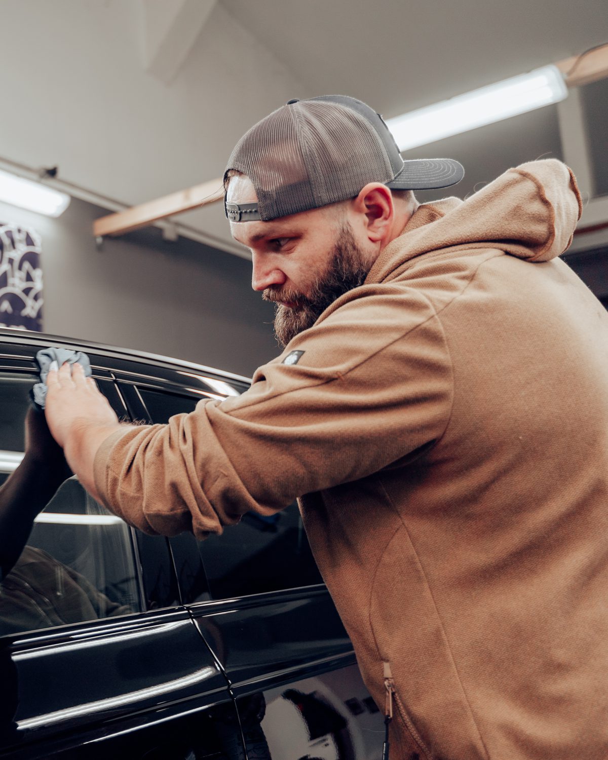 Stefan, Inhaber von The Polisher, beim Finish an einem schwarzen Sportwagen